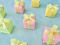 Three-color square gift boxes are arranged on a background of blue watercolor texture, pink, green and yellow. Royalty Free Stock Photo