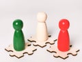 Three color wooden figures on jisaw puzzle pieces against white background. Royalty Free Stock Photo