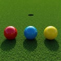 Three colored balls on the grass opposite the golf hole. Royalty Free Stock Photo