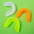 Three colored boxing mouth guards lie on a green background, concept