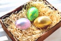 Three colored chicken eggs in a box with shavings in the sunlight Royalty Free Stock Photo