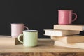 three colored cups and books on wooden table on black Royalty Free Stock Photo