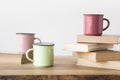 three colored cups and books on wooden table on white Royalty Free Stock Photo