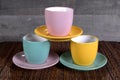 Three colored cups and saucers on wooden background Royalty Free Stock Photo