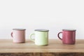 three colored cups on wooden table on white Royalty Free Stock Photo