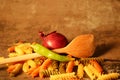 Three-colored pasta with cooking spoon on stone background