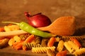 Three-colored pasta with cooking spoon on stone background