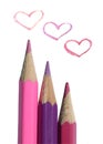 Three colored pencils and three painted hearts on white background