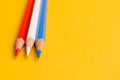 Three colored pencils on yellow background Royalty Free Stock Photo