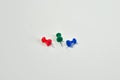 Three colored push pins on white background