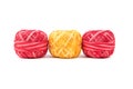 Three colored sewing threads in a row on a white background. Red and yellow threads