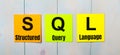 Three colored stickers with the text SQL Structured Query Language a light blue wooden background