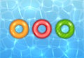 Three Colored Swim Rings on Water Background