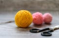 Three colored wool balls, knitting needles and scissors on the wooden background Royalty Free Stock Photo