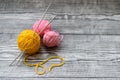 Three colored wool balls, knitting needles on the wooden background Royalty Free Stock Photo