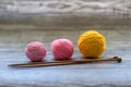 Three colored wool balls, knitting needles on the wooden background Royalty Free Stock Photo