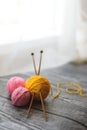 Three colored wool balls, knitting needles on the wooden background Royalty Free Stock Photo