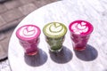 Three colorful Beetroot, matcha lattes on marble table background