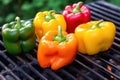 three colorful bell peppers on a charcoal grill