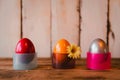 Three colorful easter eggs in holders on a wooden surface Royalty Free Stock Photo