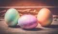 three colorful eggs sitting on top of a wooden table next to a basket of strawberries on a tablecloth covered tablecloth with a Royalty Free Stock Photo