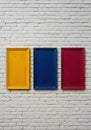 Three colorful empty frames hanging on a white brick wall, creating a vibrant and minimalist display Royalty Free Stock Photo