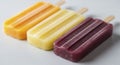 Three colorful fruit popsicles including orange, lemon, and grape flavors for summer refreshment Royalty Free Stock Photo
