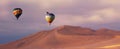 Three colorful hot air balloons over the sand dunes in Namib Desert. Artistic picture.