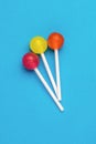 Three colorful lollipops on sticks on a blue background. Minimal concept. Sweet candies Royalty Free Stock Photo