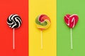 Three colorful lollipops on a white stick over a red, yellow, green background. Top view, copy space Royalty Free Stock Photo