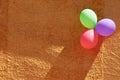 Three colorful party balloons and orange textured wall Royalty Free Stock Photo