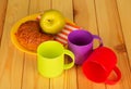 Three colorful plastic cups, a croissant and an Apple on plate, on background of table Royalty Free Stock Photo