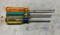 Three colorful screwdrivers lined up on a work surface.