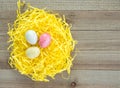 Three colorful speckled Easter eggs in yellow Easter grass on a wooden background Royalty Free Stock Photo