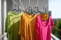 Three colorful t-shirts hanging to dry outside on the balcony. Drying clothes on the terrace in the city Royalty Free Stock Photo