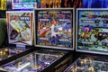 Three colorful vintage pinball machines in arcade