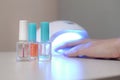 Three colorless transparent nail polish bottles in background of female hands in gel uv led nail white lamp for drying manicure Royalty Free Stock Photo