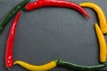 Three colorsr chili peppers on a dark slate stone slab