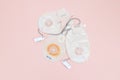 Three colostomy bags with medical clips lie on a pale pink background,