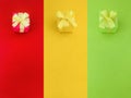 Three colour red, yellow and green gift boxes with a yellow satin ribbon bow on their same color background. Royalty Free Stock Photo