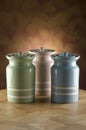 Three colourful ceramic canisters on timber bench with rustic background