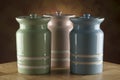 Three colourful ceramic canisters on timber bench with rustic background