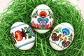 Three Colourful Easter Eggs with floral and roosters folk art pattern printed on stickers, in green paper grass nest. Royalty Free Stock Photo