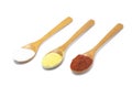 Three common spices in wooden spoons isolated on white background Royalty Free Stock Photo