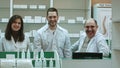 Three competent pharmacists laughing in a pharmacy looking at camera