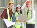 Three confident construction team, a female architect and two male engineers, wearing safety helmets,holding computer and blue Royalty Free Stock Photo