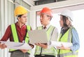 Three confident construction team, a female architect and two male engineers, wearing safety helmets,holding computer and blue Royalty Free Stock Photo