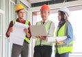 Three confident construction team, a female architect and two male engineers, wearing safety helmets,holding computer and blue Royalty Free Stock Photo