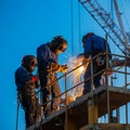 Three construction workers wearing protective helmets and blue overalls are welding Royalty Free Stock Photo