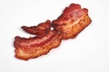 Three cooked, crispy fried bacon isolated on a white background.